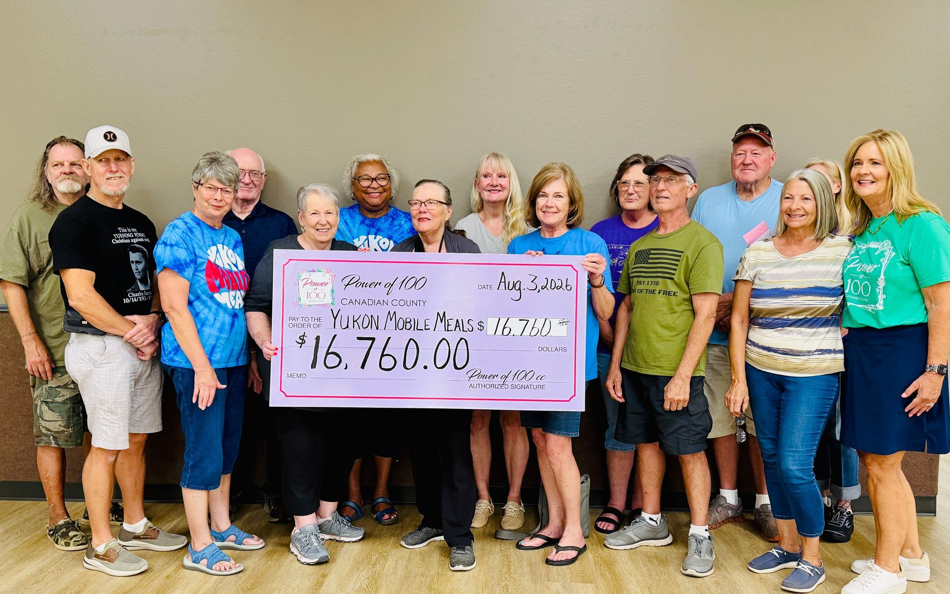 A group of people standing next to each other holding a large pink check.