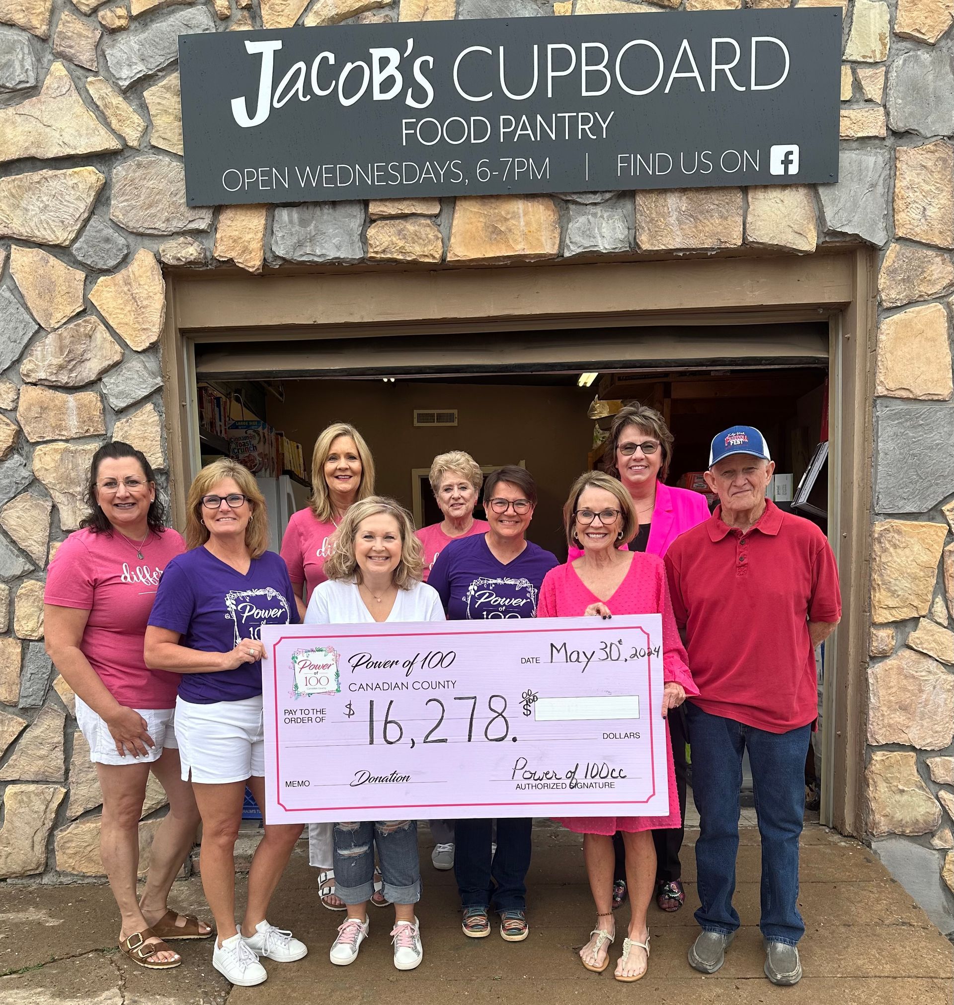 A group of people holding a check in front of jacob 's cupboard