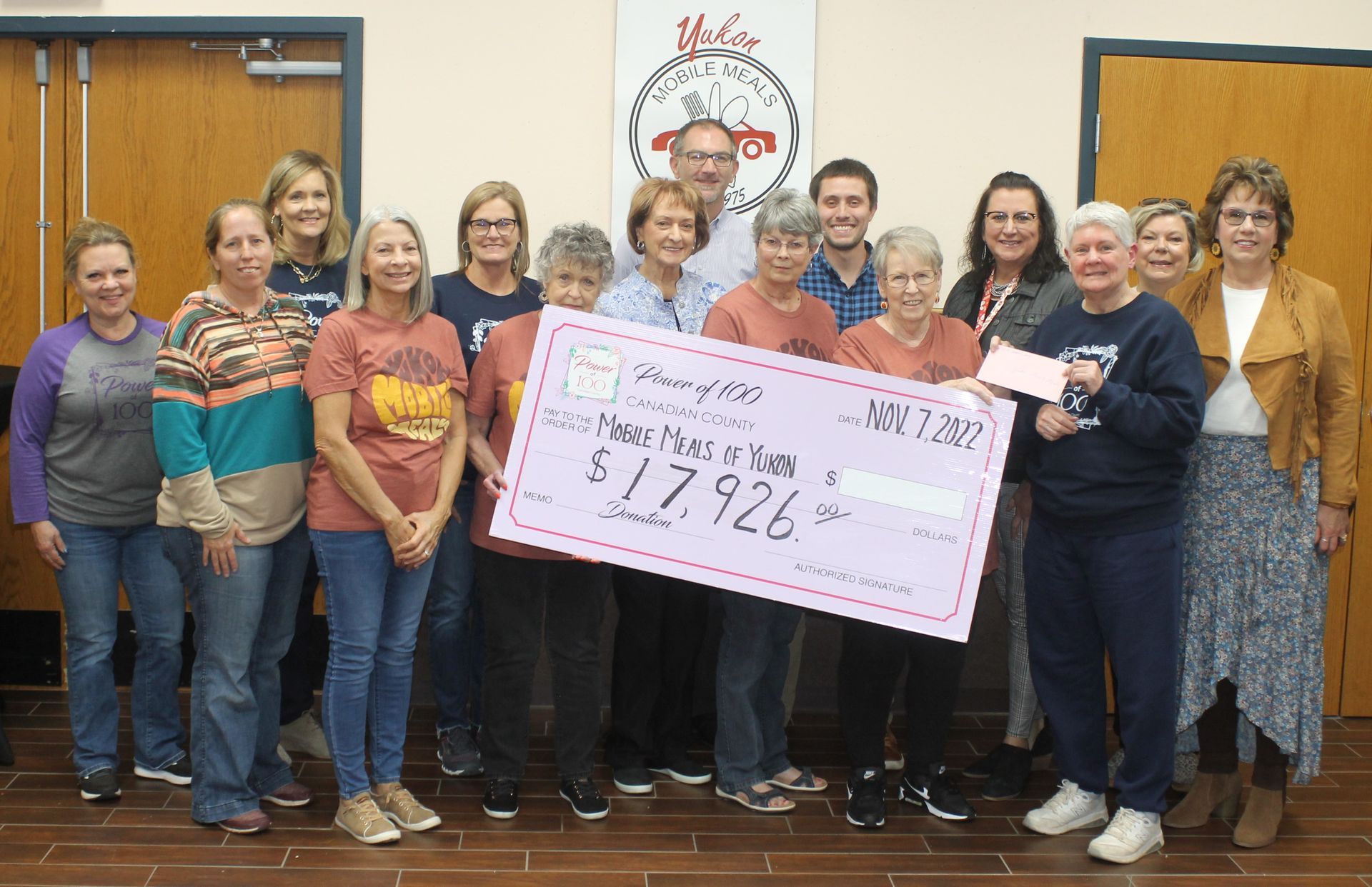A group of people standing next to each other holding a large check.