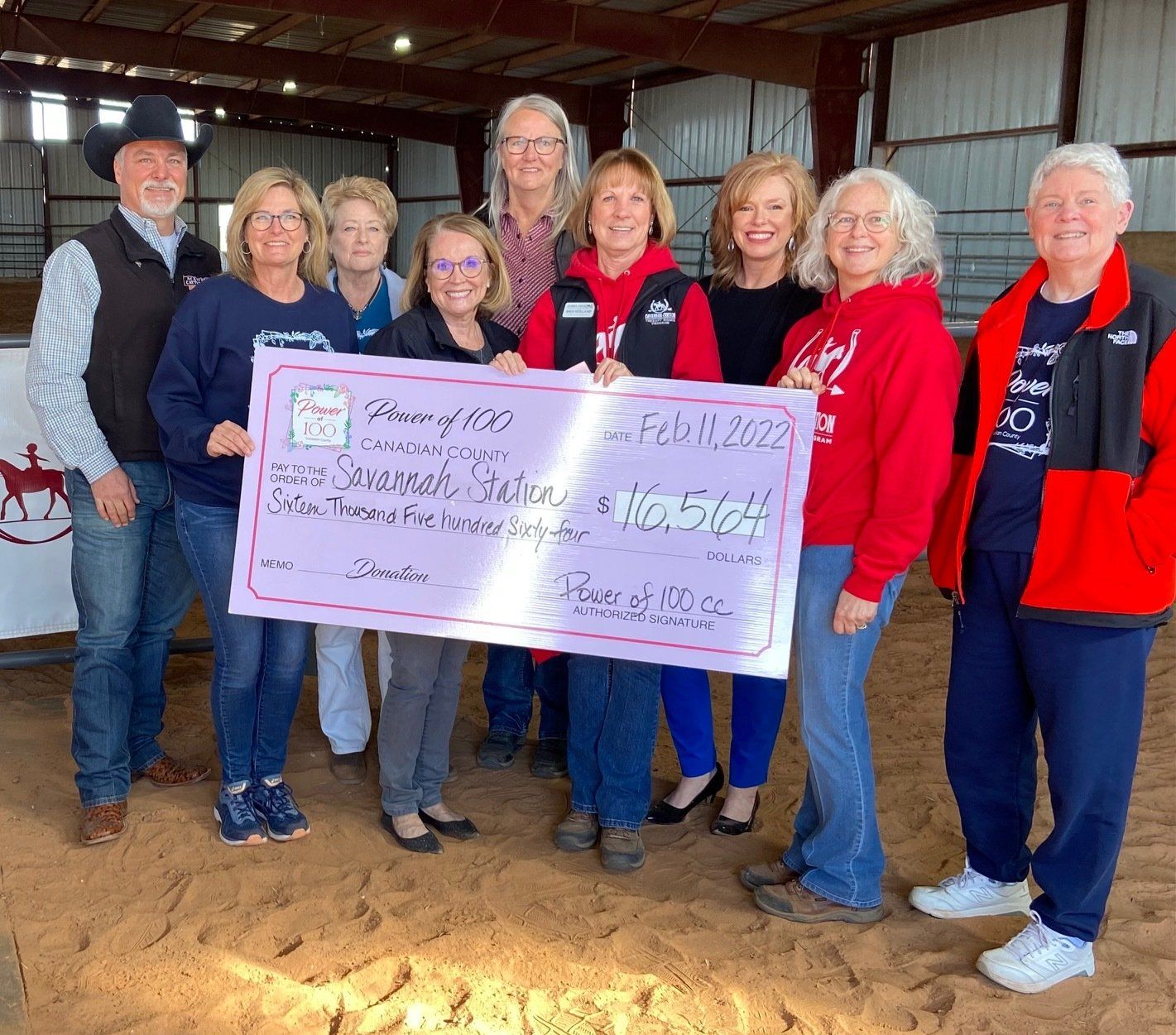A group of people are posing for a picture while holding a large check