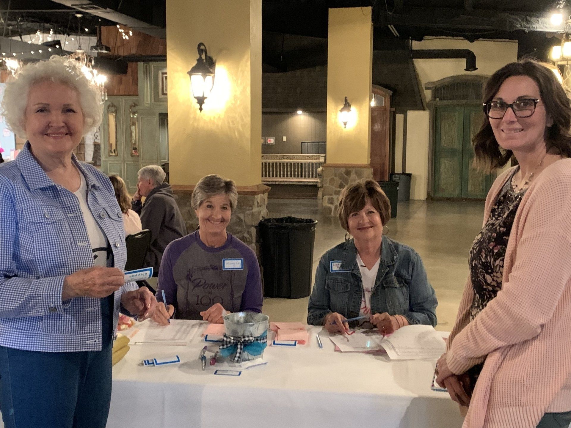 A group of women are standing around a table in a room.