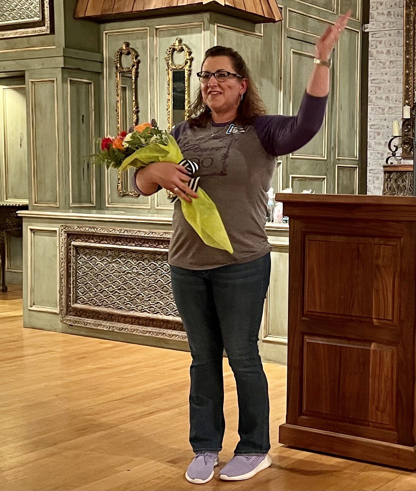 A woman is holding a bouquet of flowers and waving