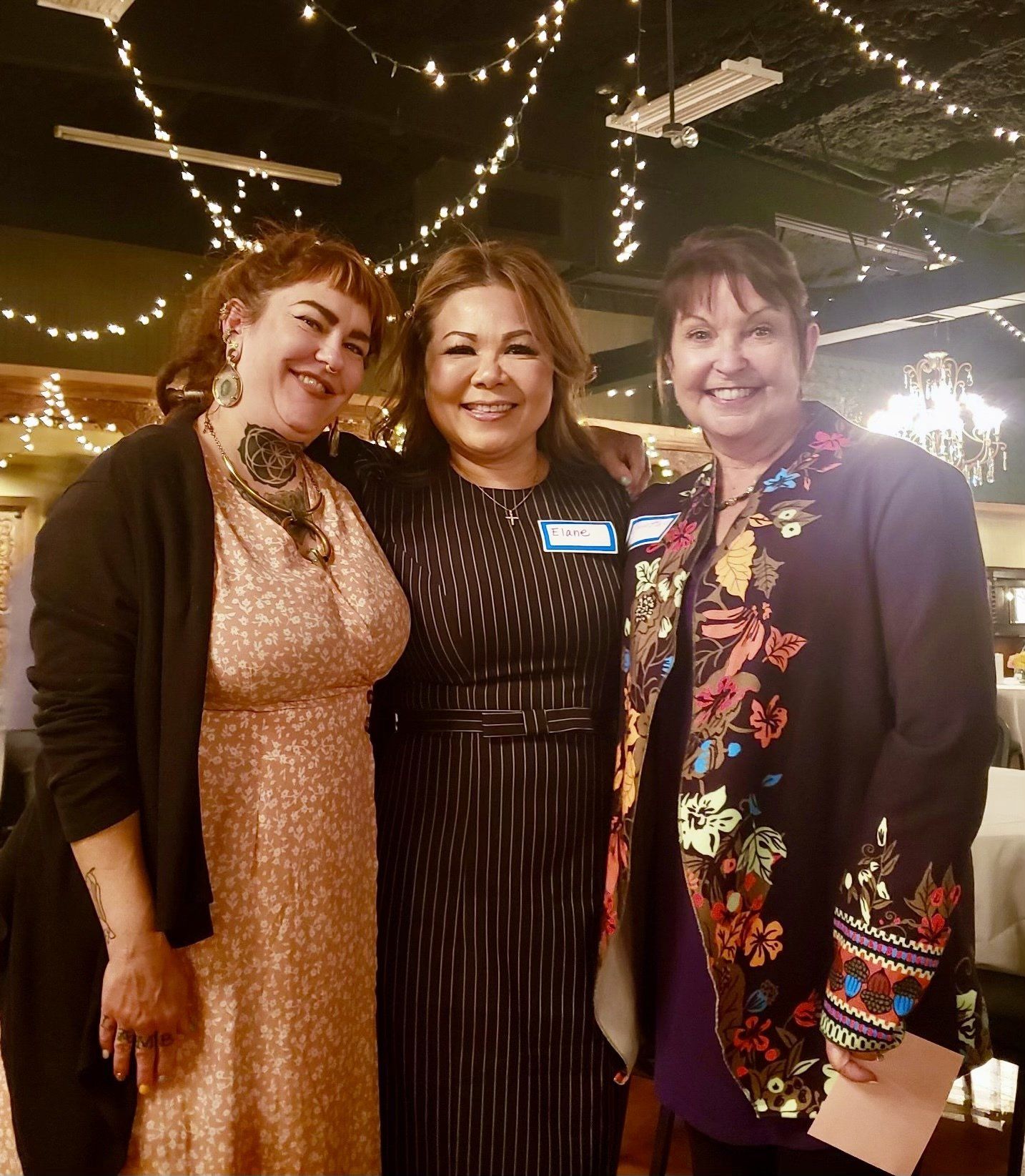 Three women are posing for a picture together in a restaurant.