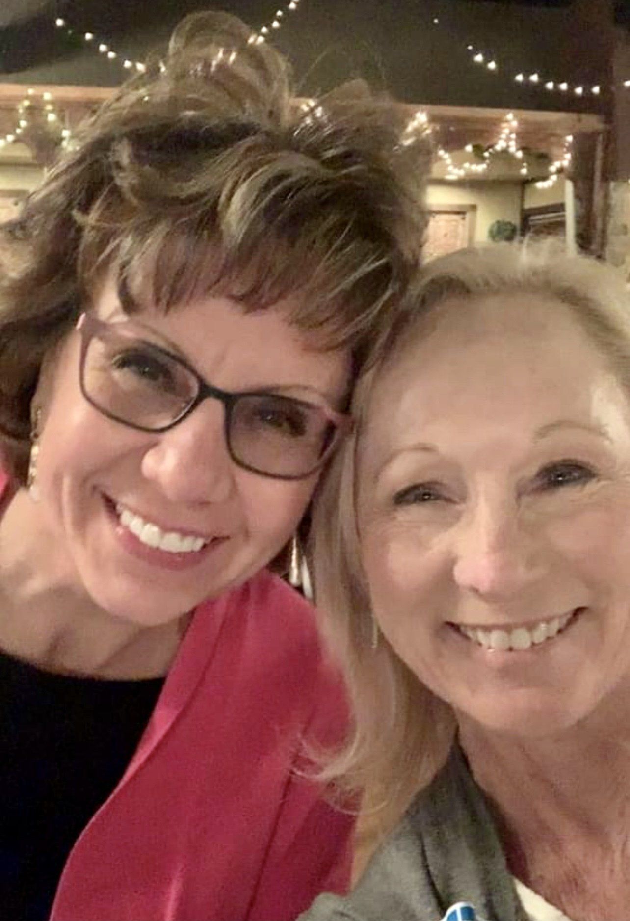 Two women are posing for a picture together and smiling for the camera.