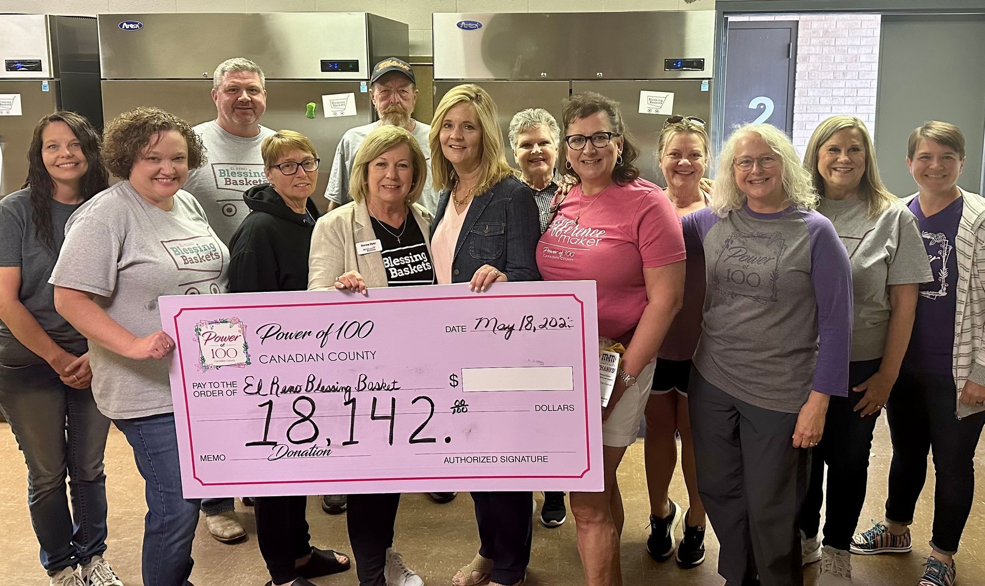 A group of people are standing next to each other holding a large check.