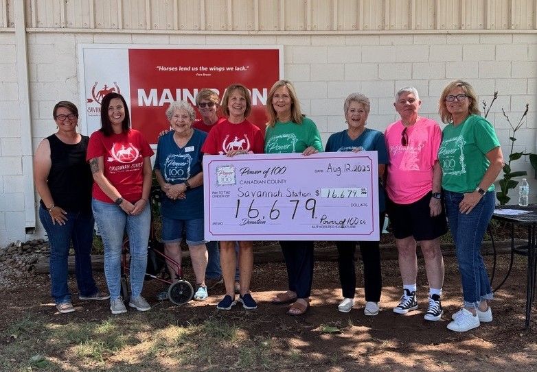 A group of women are posing for a picture while holding a large check.