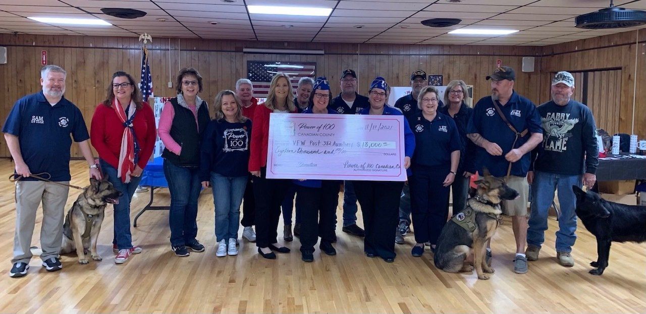 A group of people standing in a room holding a check.