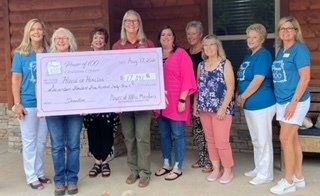 A group of women standing next to each other holding a large check.