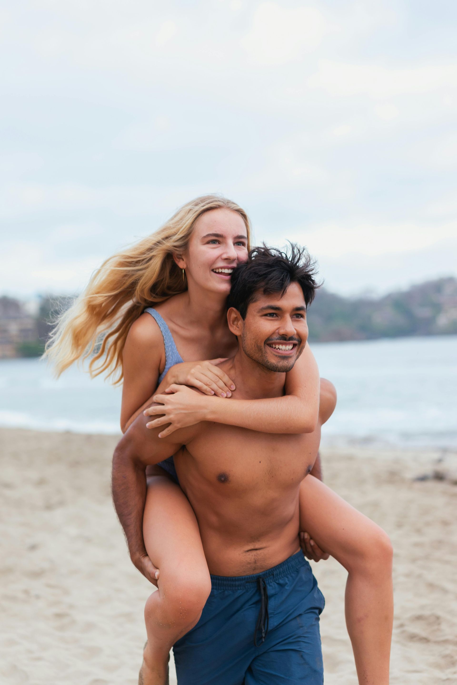 two  people  on a beach withcalm water under a clear blue sky.
