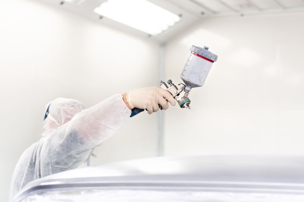 A Man Is Painting A Car In A Paint Booth — Lyons Street Paint Panel in Redlynch, QLD
