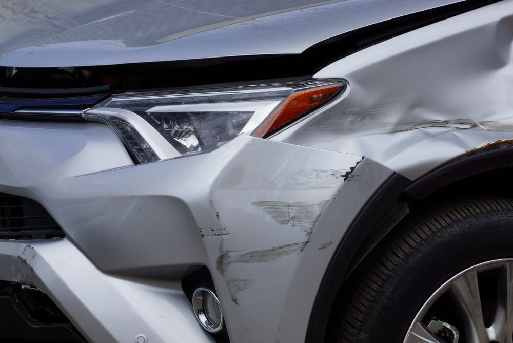 A Silver Car With A Damaged Front Bumper And Headlight — Lyons Street Paint Panel in Redlynch, QLD
