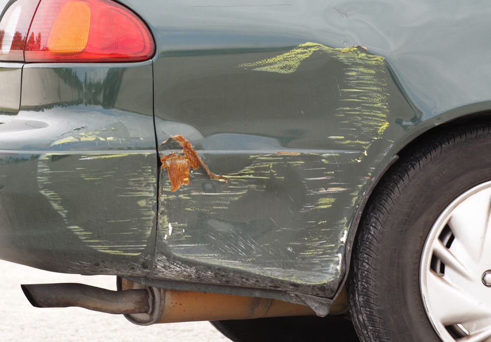 A Green Car With A Damaged Fender And Exhaust Pipe — Lyons Street Paint Panel in Bungalow, QLD