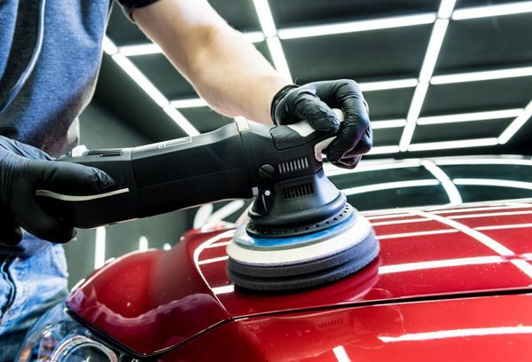 A Man Is Polishing a Black Car with A Polisher — Lyons Street Paint Panel in Bungalow, QLD