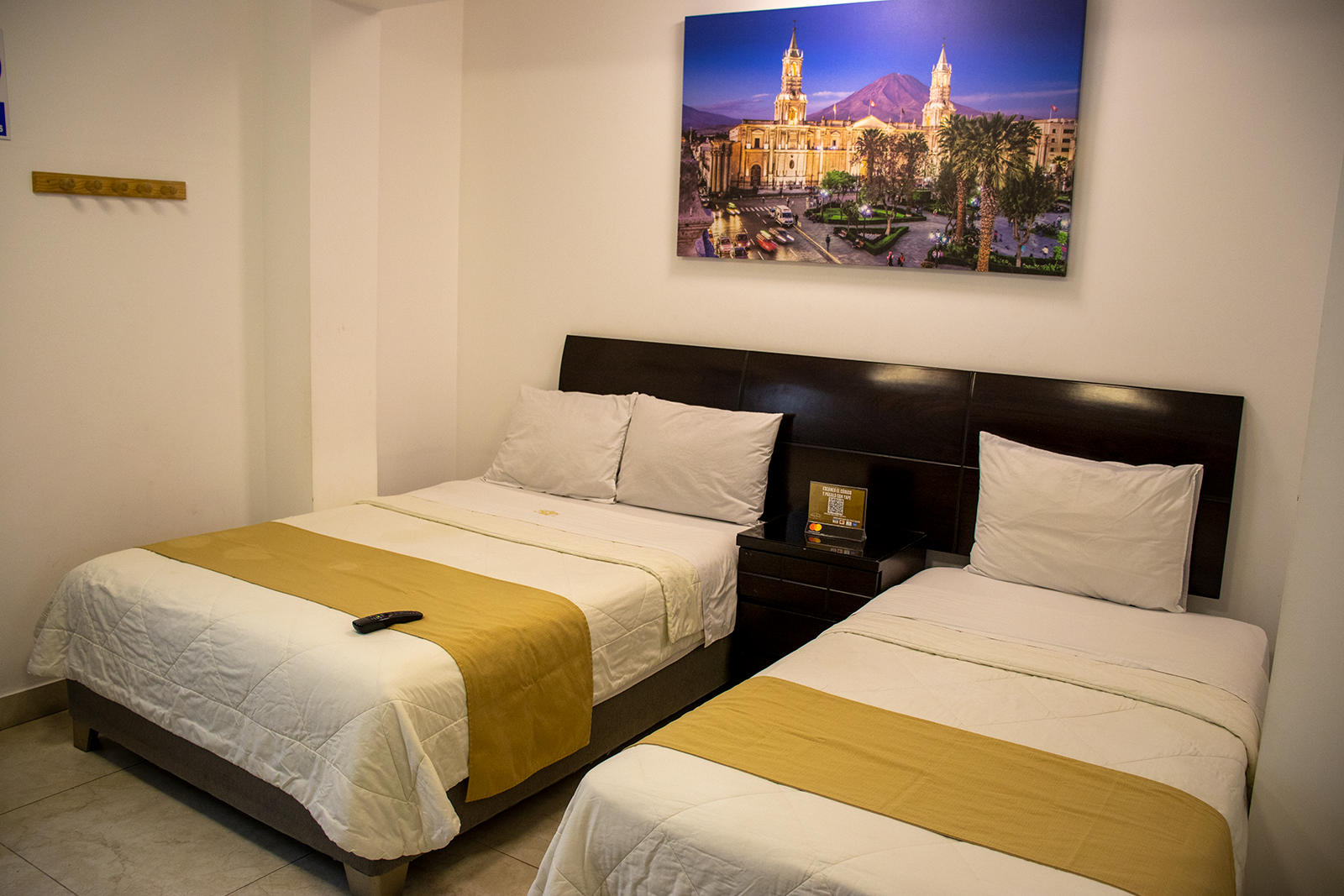 Bedroom with a queen bed and a twin bed; gold bed runners, landscape art on the wall.
