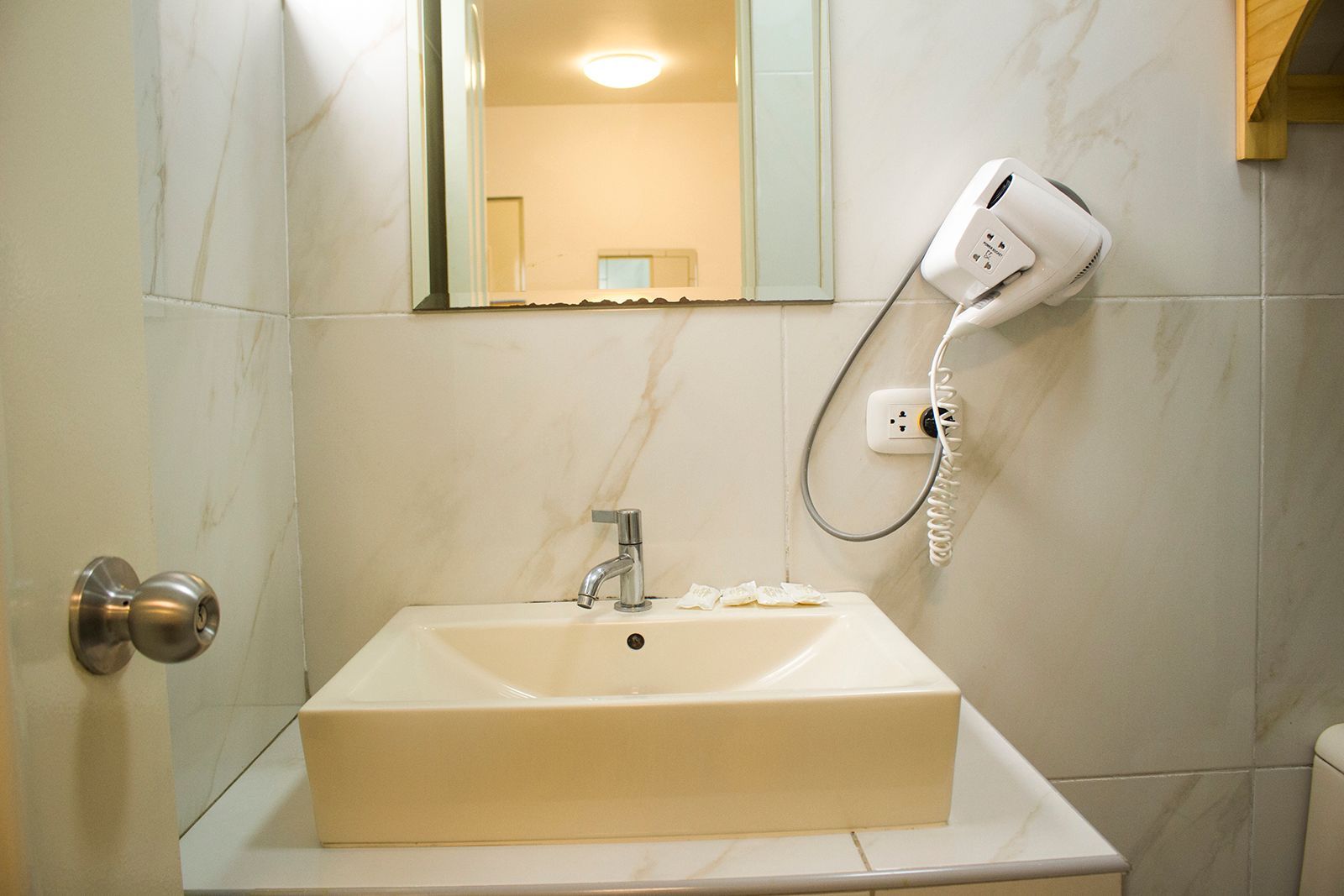 Bathroom with square sink, mirror, and hairdryer mounted on the wall.