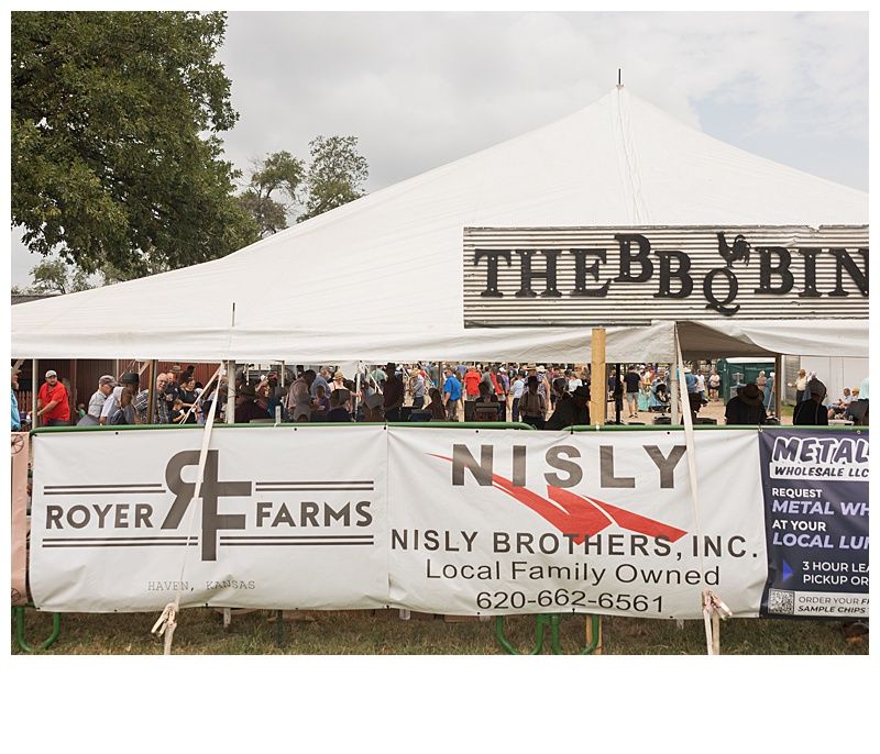 White event tent with crowd and farm-business banners at an outdoor fair