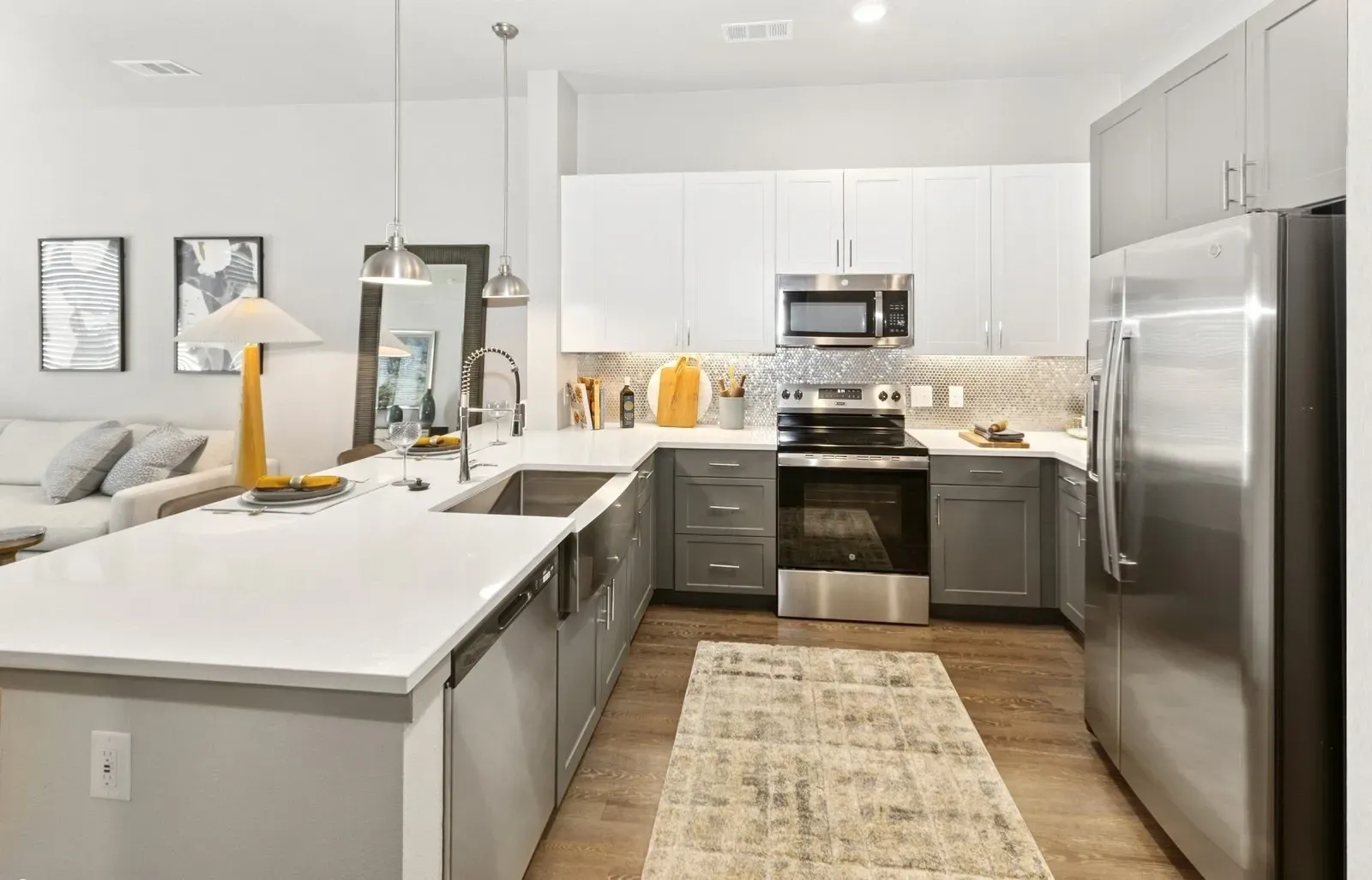 Modern apartment kitchen with stainless steel appliances, an island, and gray/white cabinets. Find your perfect fit at apartments in Rowlett, TX and see how comfort meets convenience—schedule a tour.