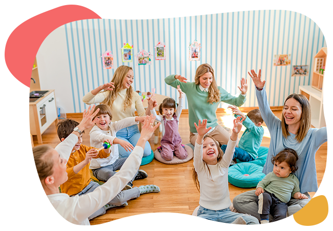 A group of people are sitting on the floor with their hands in the air.