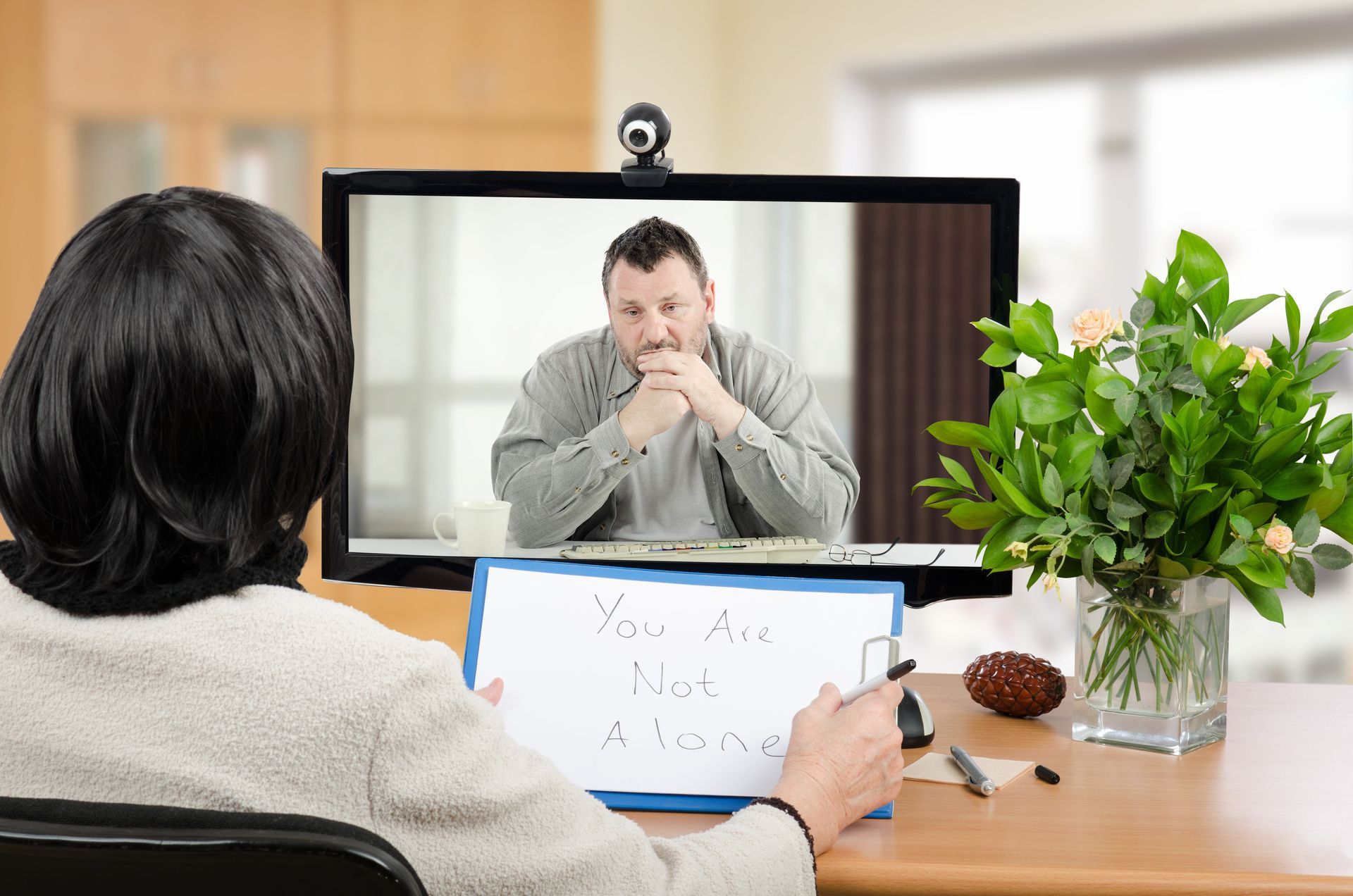 A woman is sitting in front of a computer talking to a man on a video call.