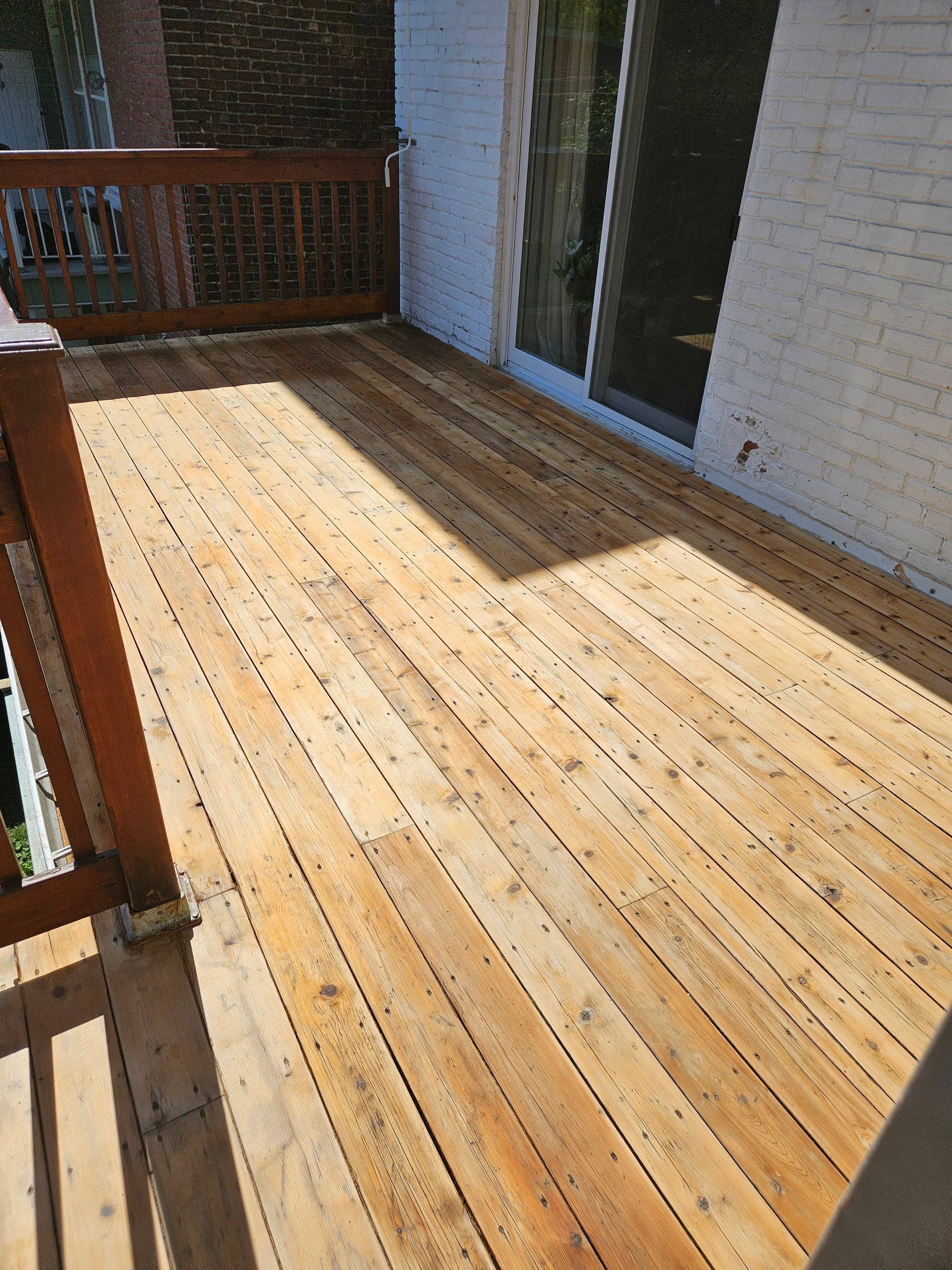 Terrasse en bois avec planches patinées, rambarde et porte coulissante en verre.