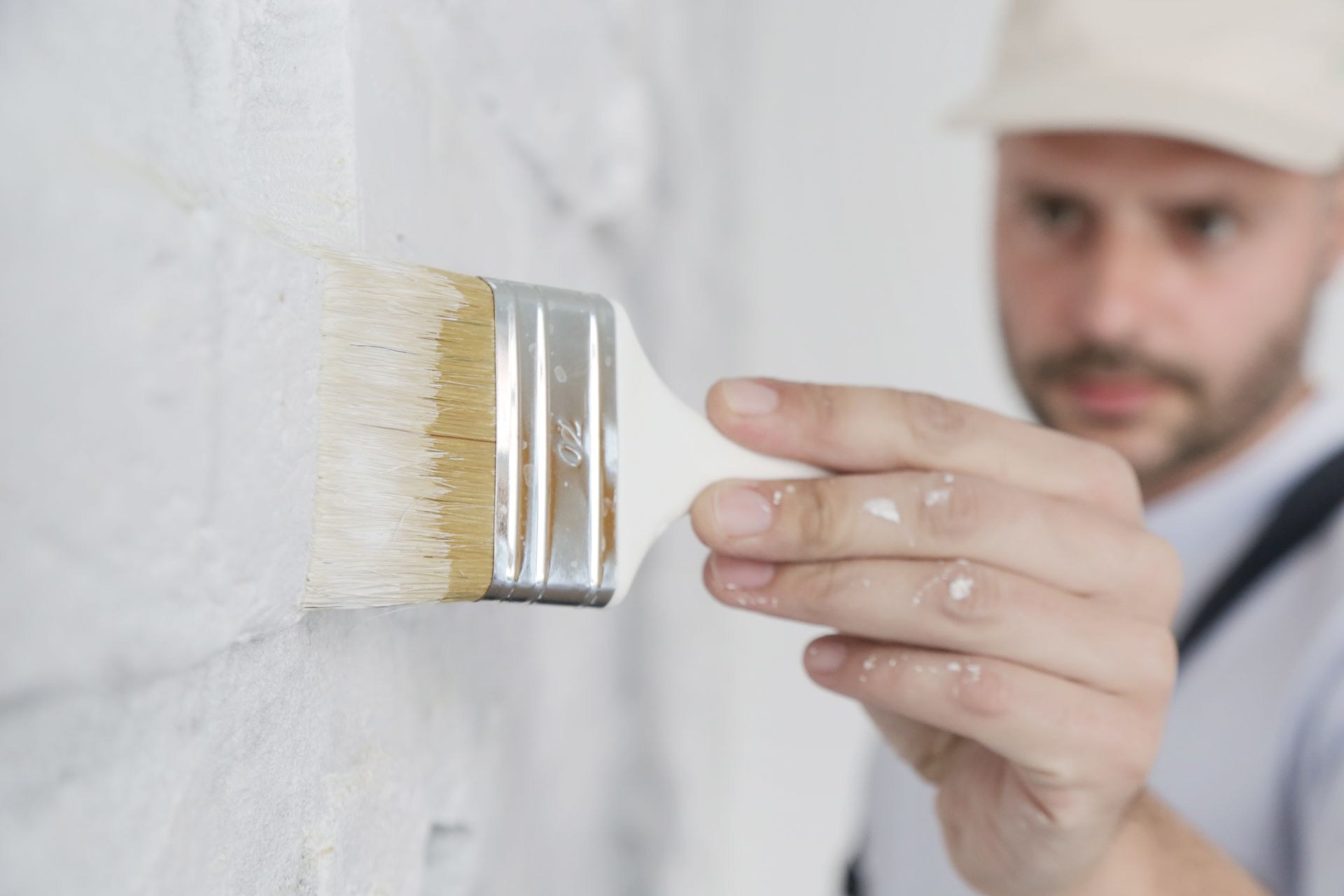 Une personne peignant un mur blanc au pinceau, gros plan.