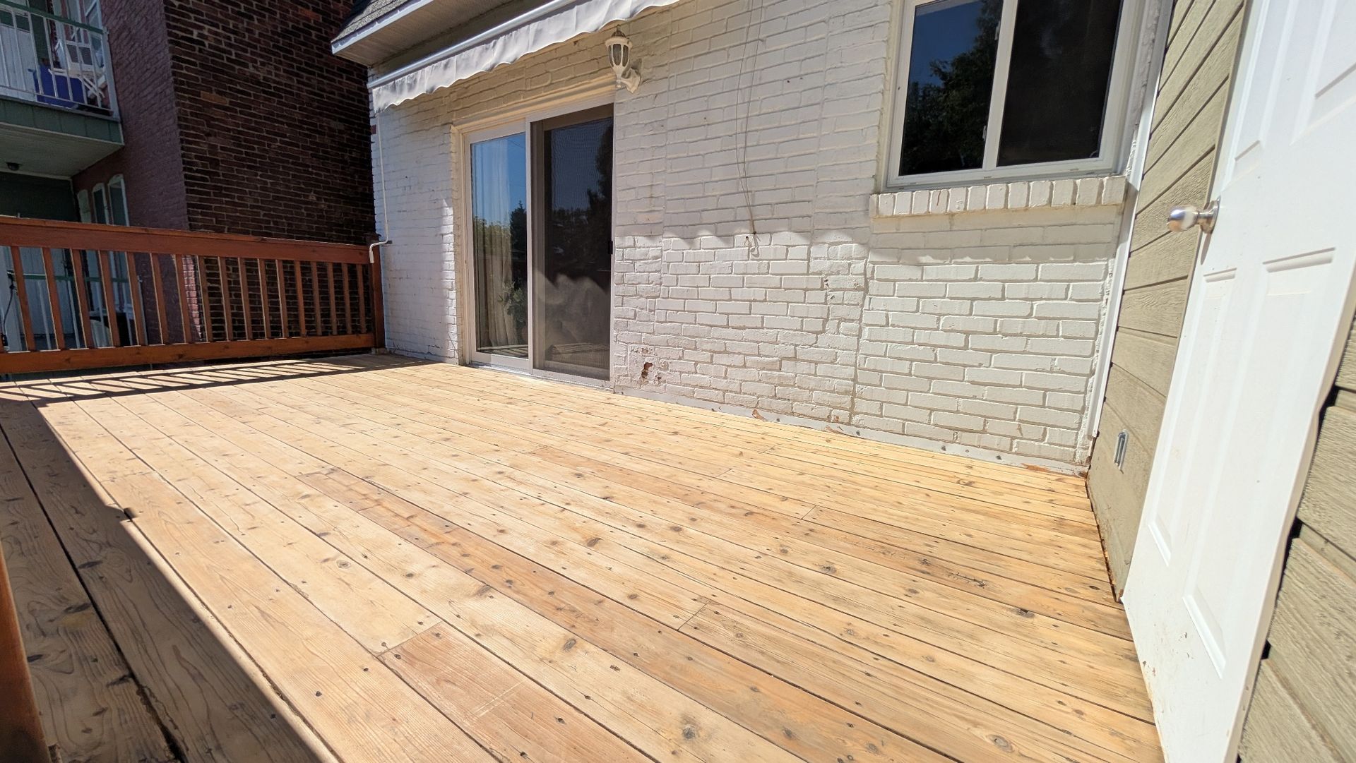 Terrasse en bois avec porte coulissante en verre et revêtement en briques.