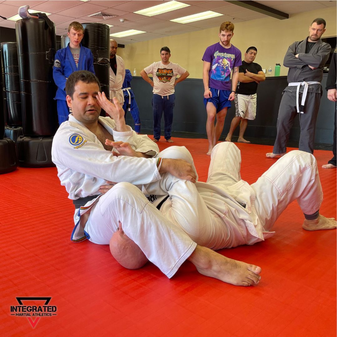 A group of men are practicing martial arts in a gym sponsored by integrated martial arts