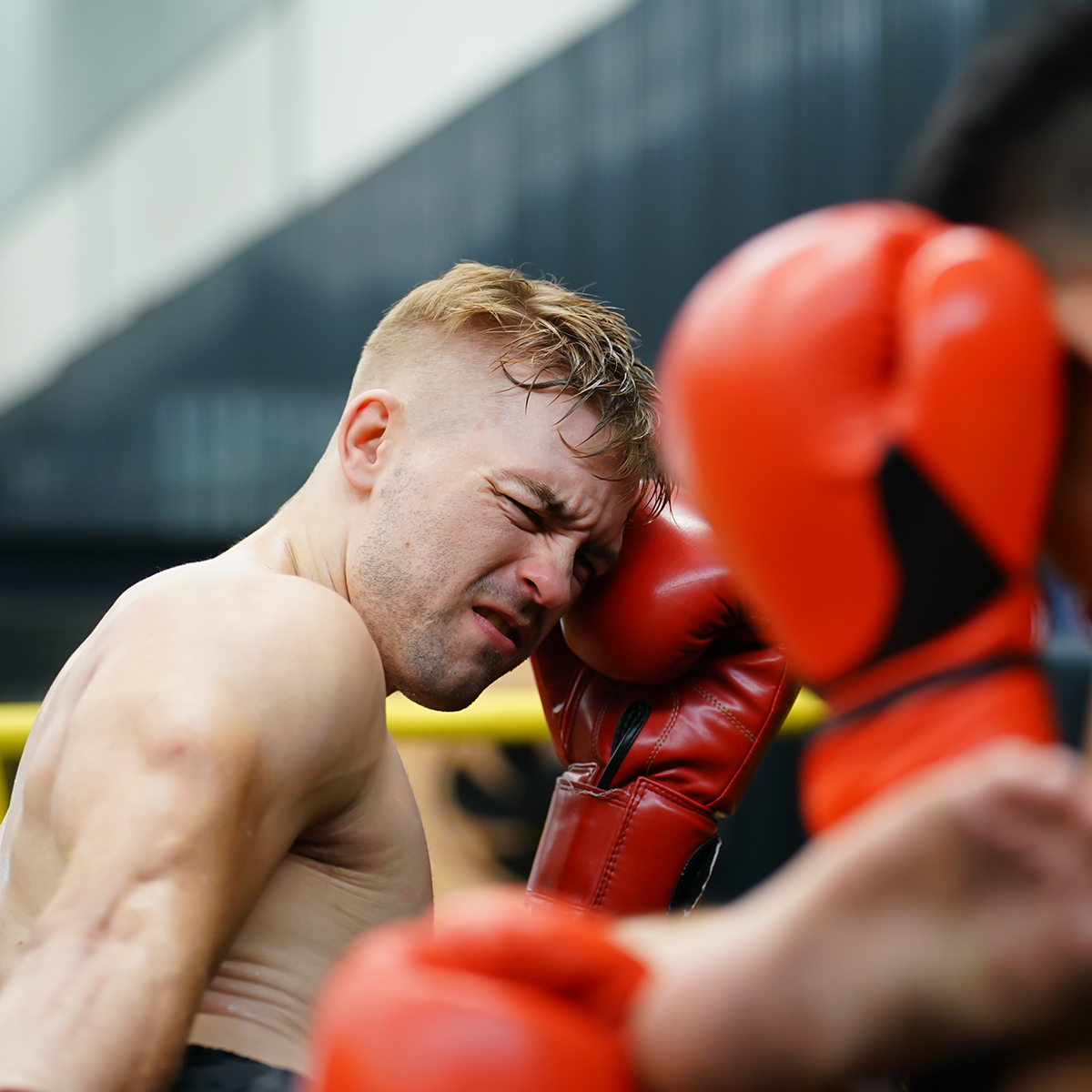 a man wearing a pair of red boxing gloves has his face in a corner