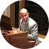 A man in a suit is sitting at a desk in a circle.