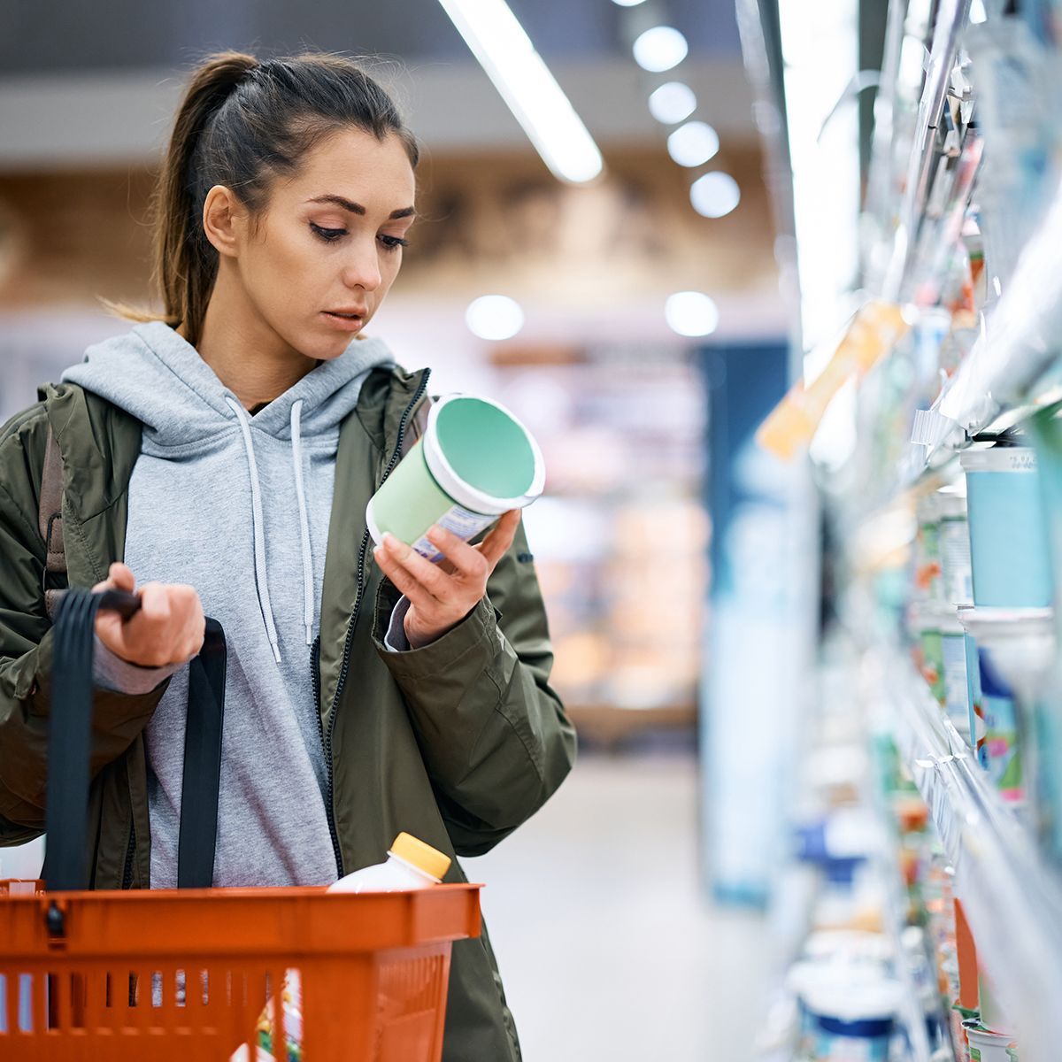 A woman is shopping in a grocery store while holding a cup.