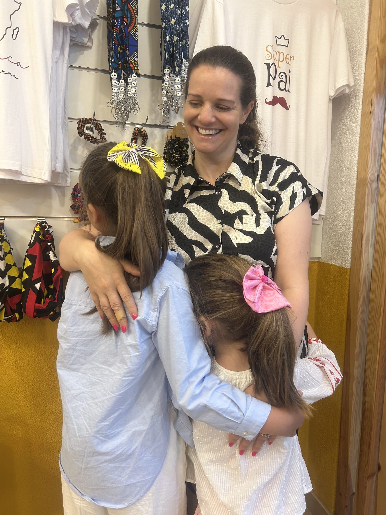 Uma mulher está abraçando duas meninas em uma loja.
