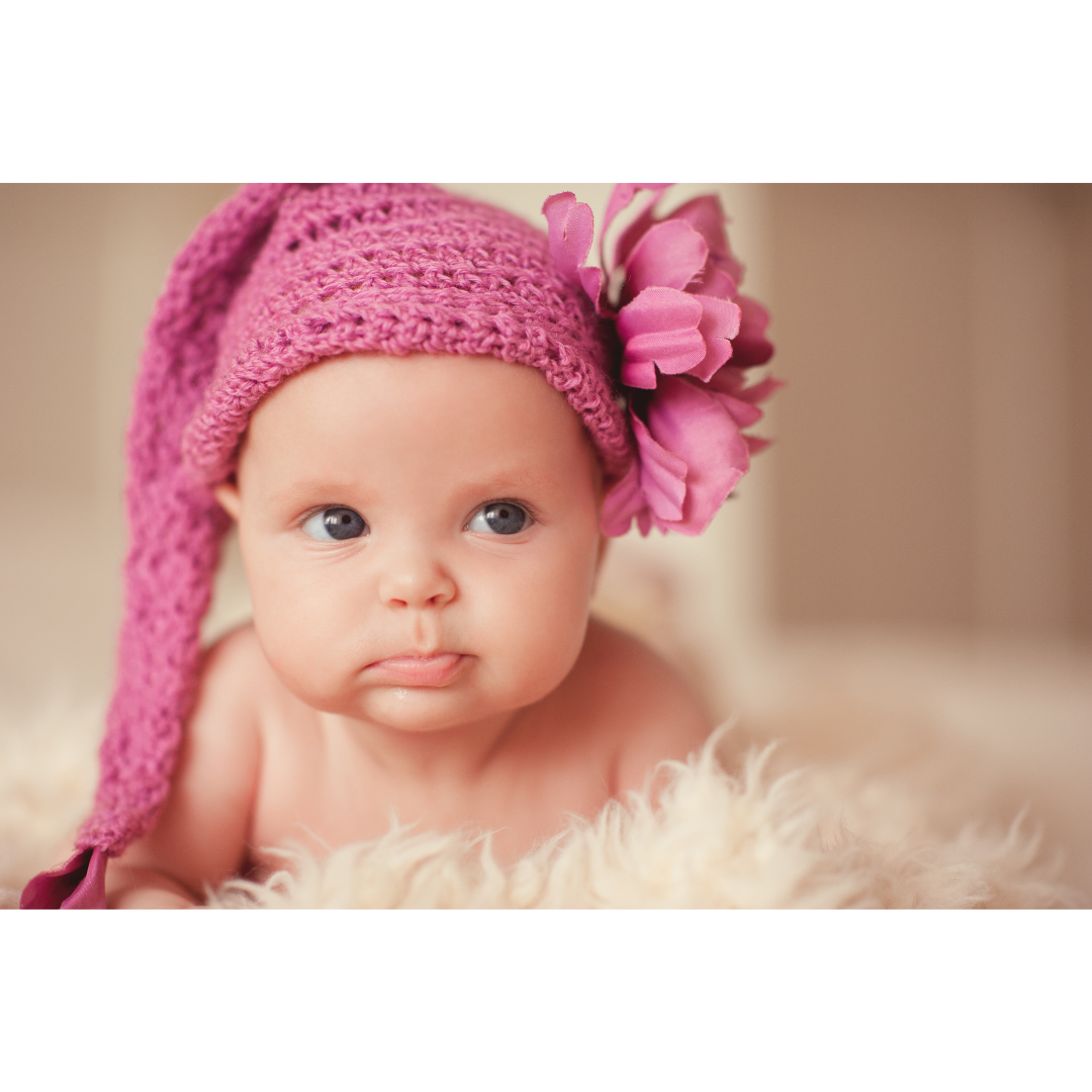 Um bebê está usando um chapéu rosa com uma flor.