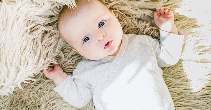 Um bebê está deitado em um cobertor fofo no chão.