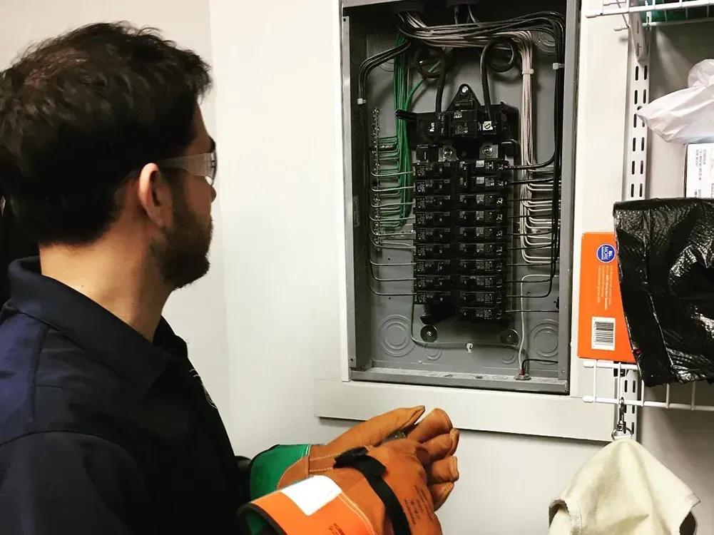 a man wearing gloves is working on an electrical box .