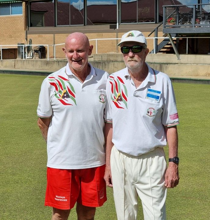 People playing lawn bowls on a sunny day. They have red and white uniforms.