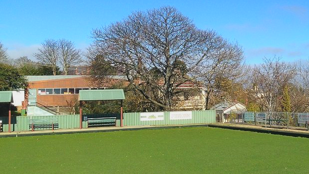Bowling green with bench seats and blue sky.