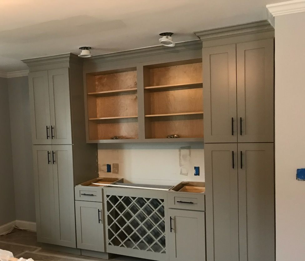 Built-in gray cabinetry with open shelves, countertop, and wine rack in a kitchen alcove.
