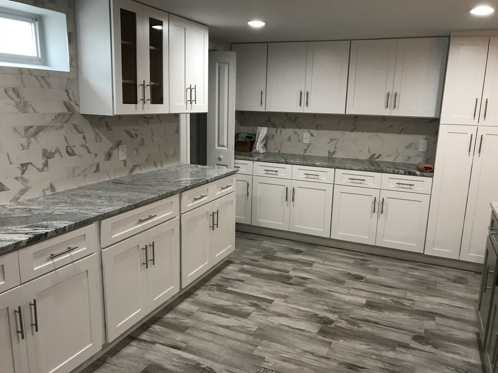 Modern kitchen with white cabinets, gray marble countertops, and gray patterned flooring