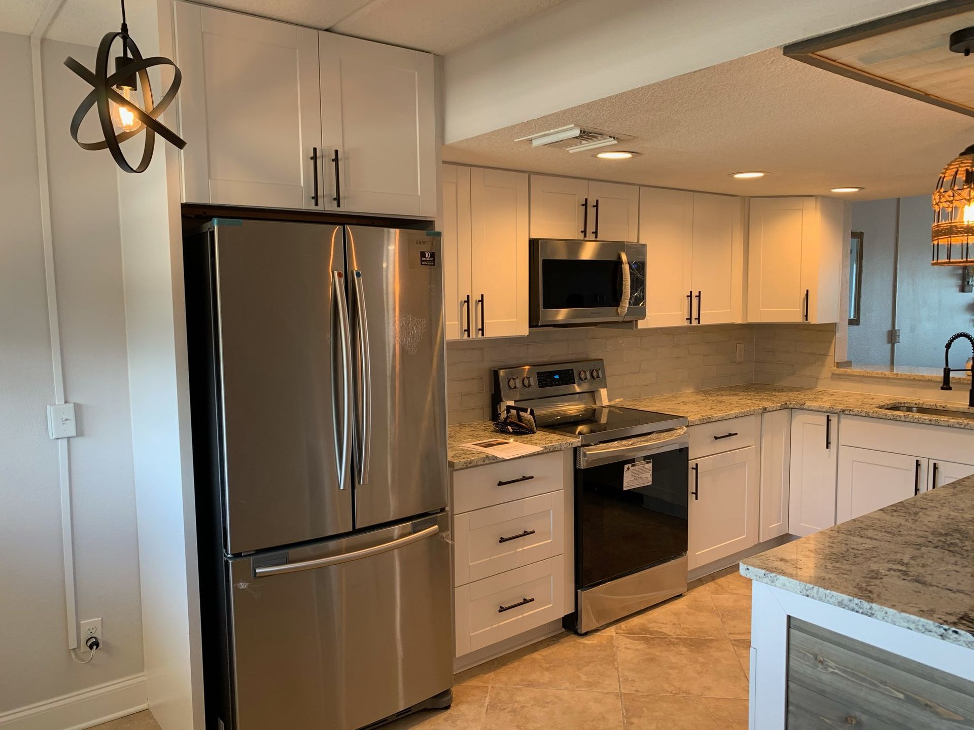 Modern kitchen with stainless steel appliances, white cabinets, and granite countertops