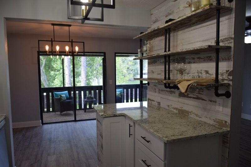 Modern kitchen with white cabinets, granite counters, open shelving, and sliding doors to a balcony.