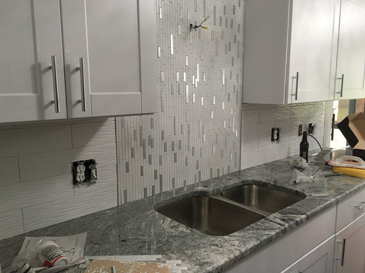 Modern kitchen with gray cabinets, mosaic tile backsplash, granite counter, and double sink