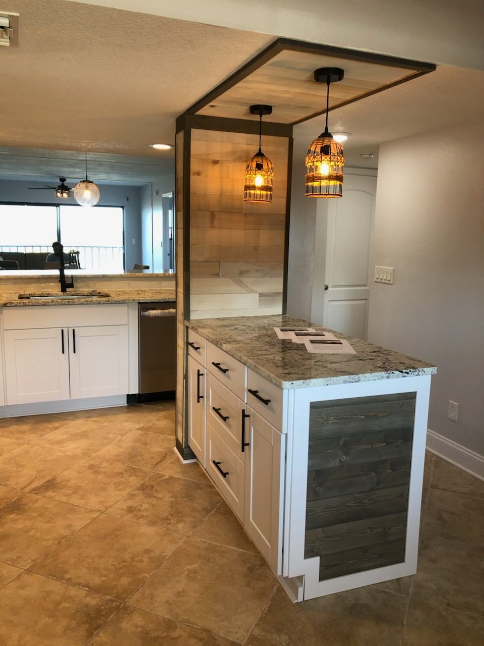 Modern kitchen with a central island, pendant lights, and white and wood cabinets