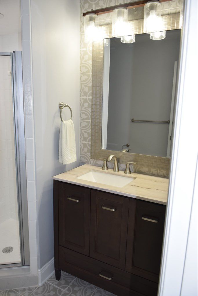 Modern bathroom vanity with mirror, wall lights, beige countertop, and dark wood cabinet