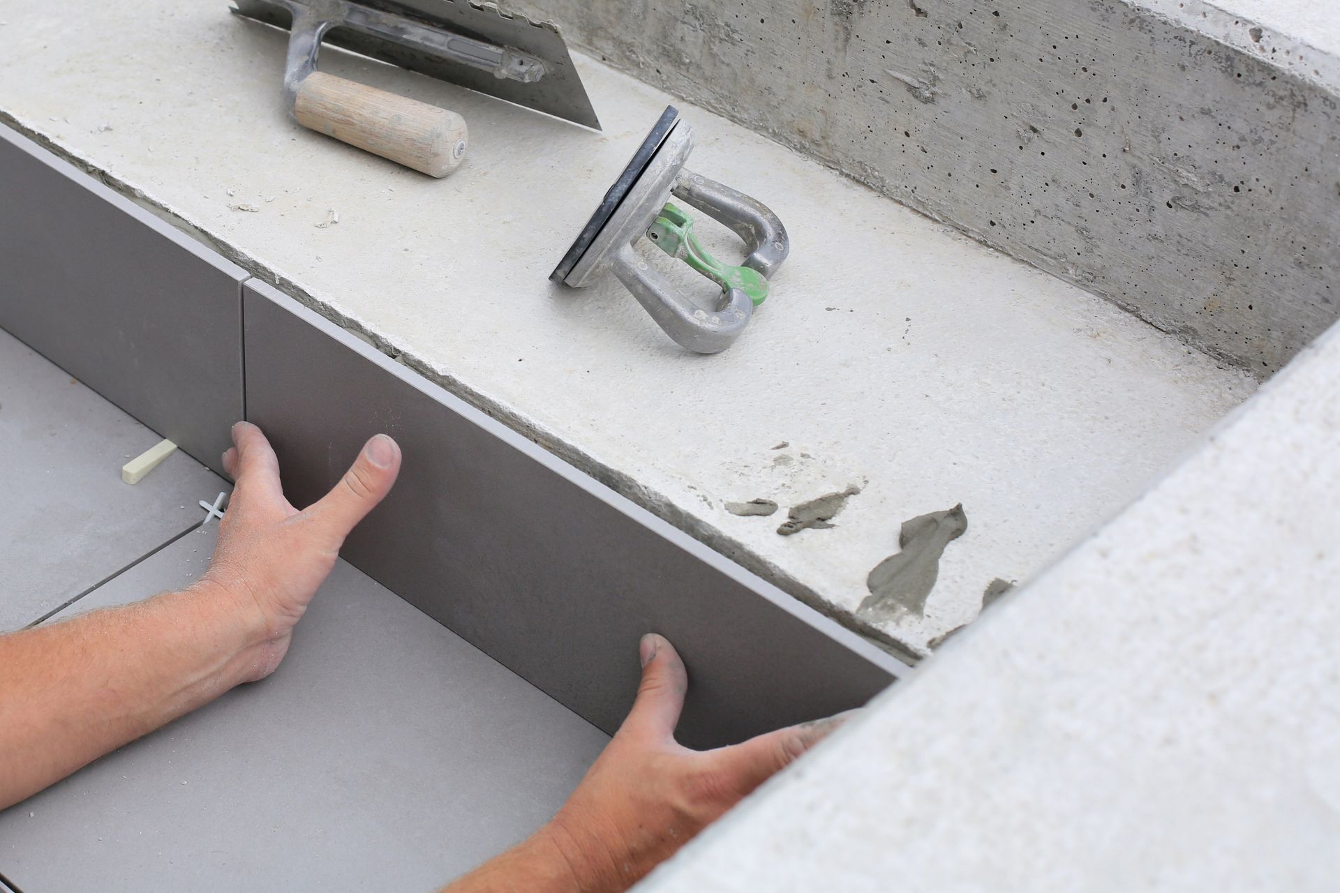 Tiler hands working on a new house entrance.
