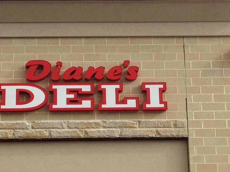 A sign for diane 's deli is on a brick wall