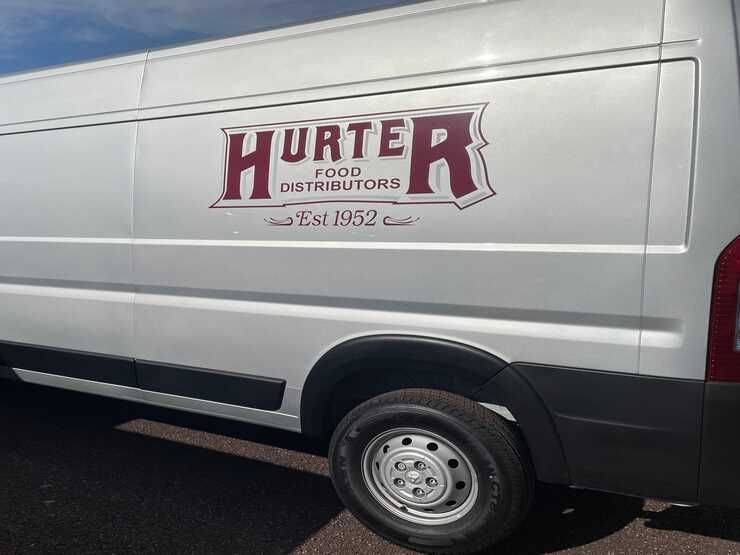 A white hunter food distributors van is parked on the side of the road