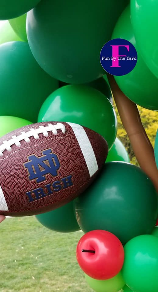 a football is sitting on top of a bunch of green balloons