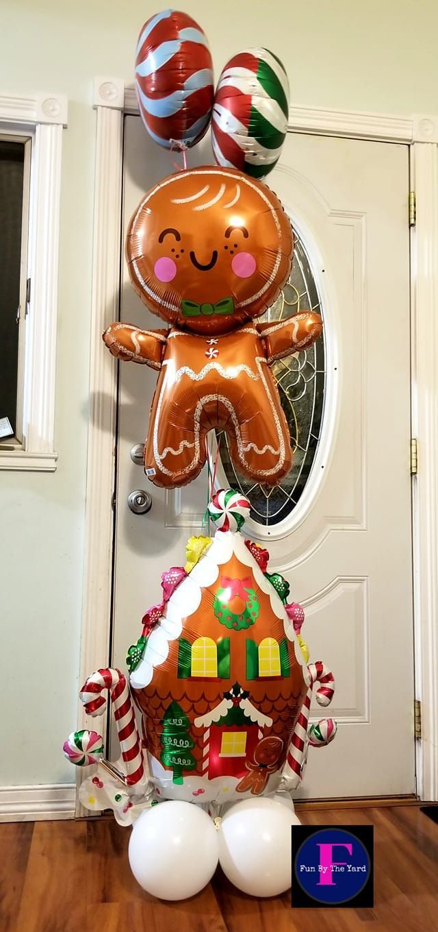 A gingerbread man balloon is sitting on top of a gingerbread house balloon.