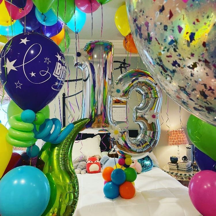 A bedroom decorated with balloons and a number 13. Party Bomb