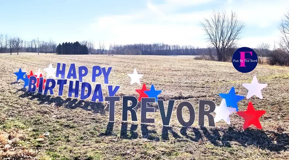 A happy birthday sign for trevor is in a field.